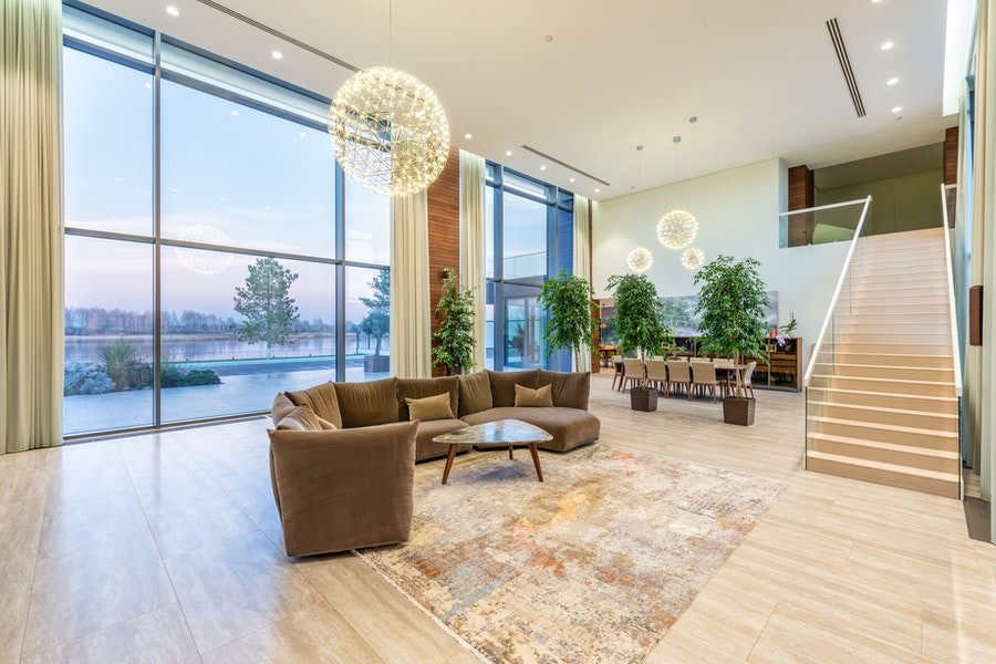 A modern living room with floor-to-ceiling windows overlooking an outdoor space with plants and a pool