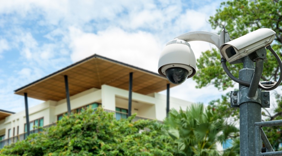  Image is of a security camera in focus and a blurred building in the background.