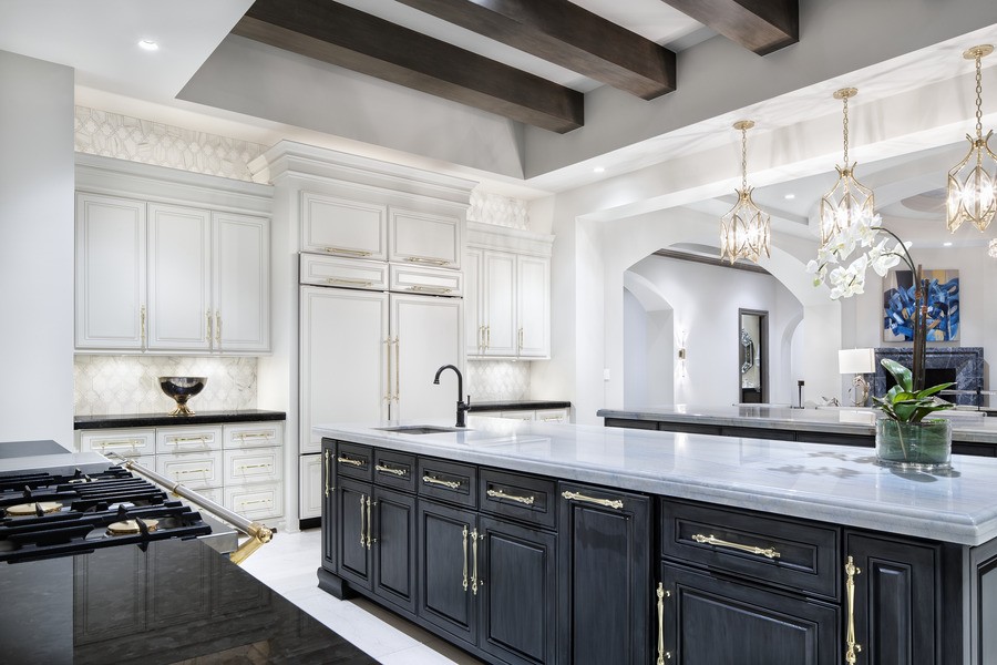 A bright, white kitchen with black cabinets illuminated by Lutron lighting.