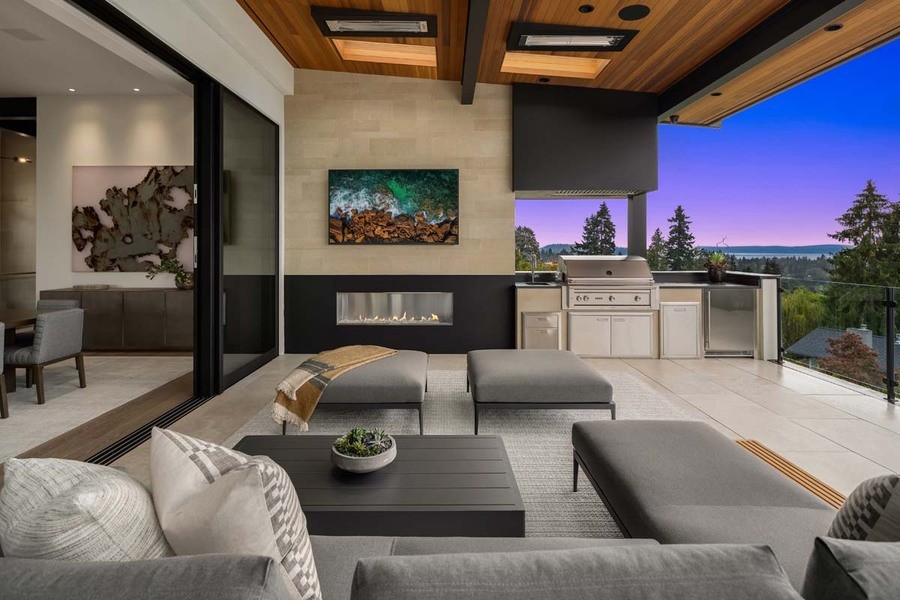 An elegant open-plan living space that seamlessly transitions to an outdoor patio area. The interior features a modern gas fireplace and comfortable seating in neutral tones.